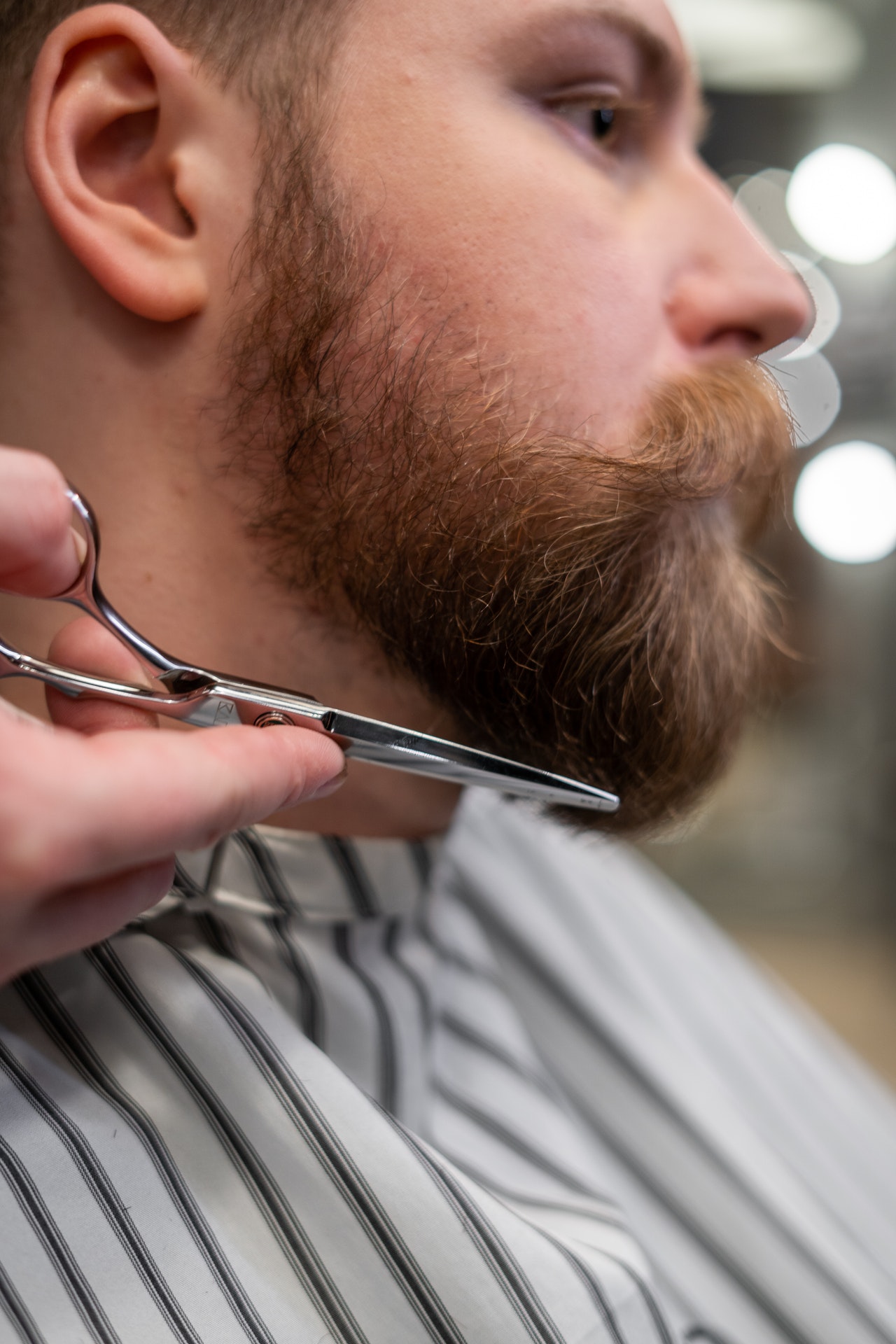Man Having his Beard Trimmed with Scissors